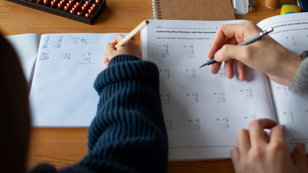 Parent reviewing a child's fractions worksheet with a pen